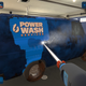 A screenshot from PowerWash Simulator depicting a very grimy van getting washed clean.